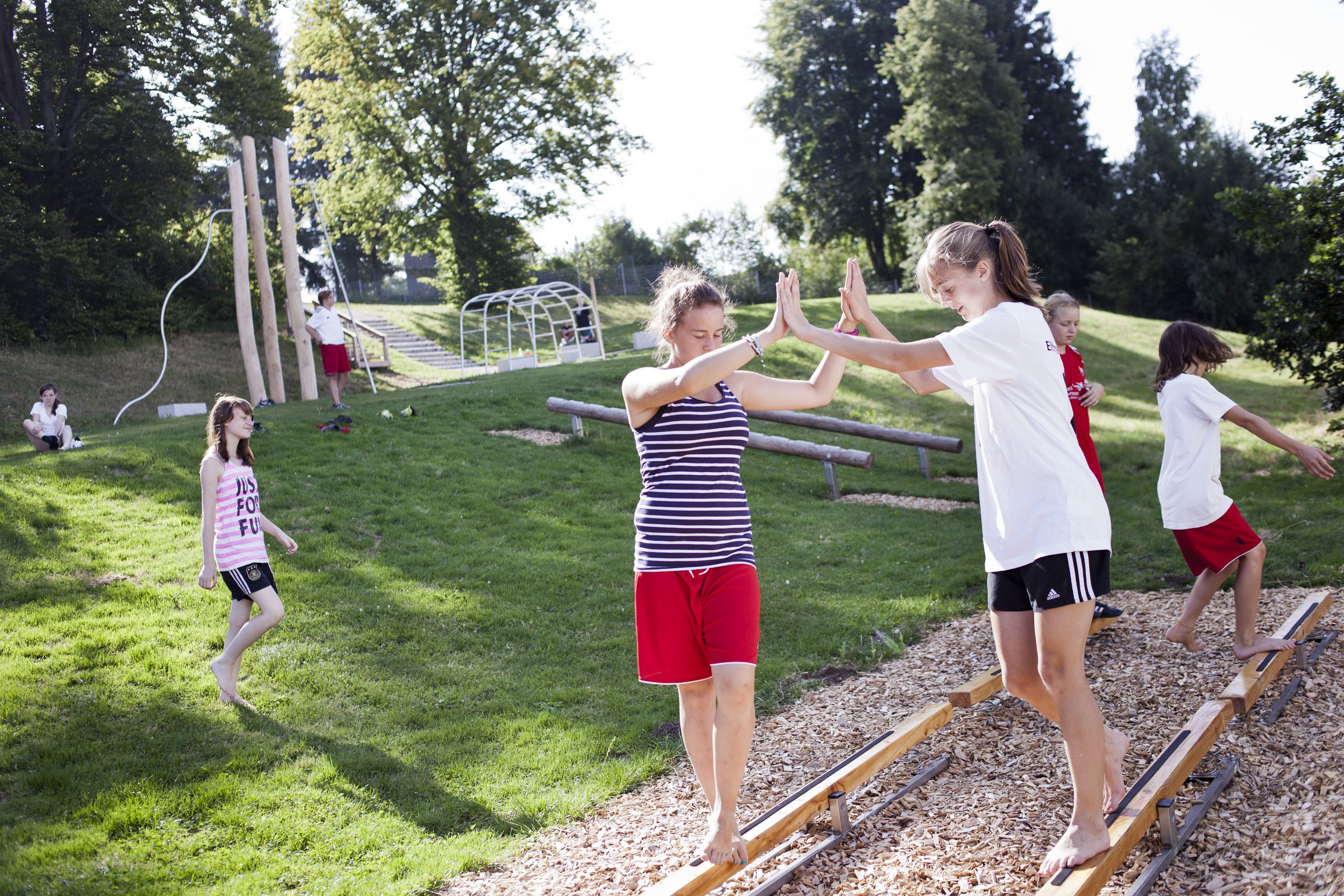 Mehrere Kinder spielen im Freien auf einem Spielplatz im Grünen.